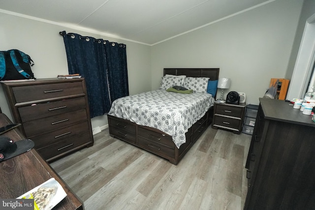 bedroom with crown molding, light hardwood / wood-style floors, and vaulted ceiling