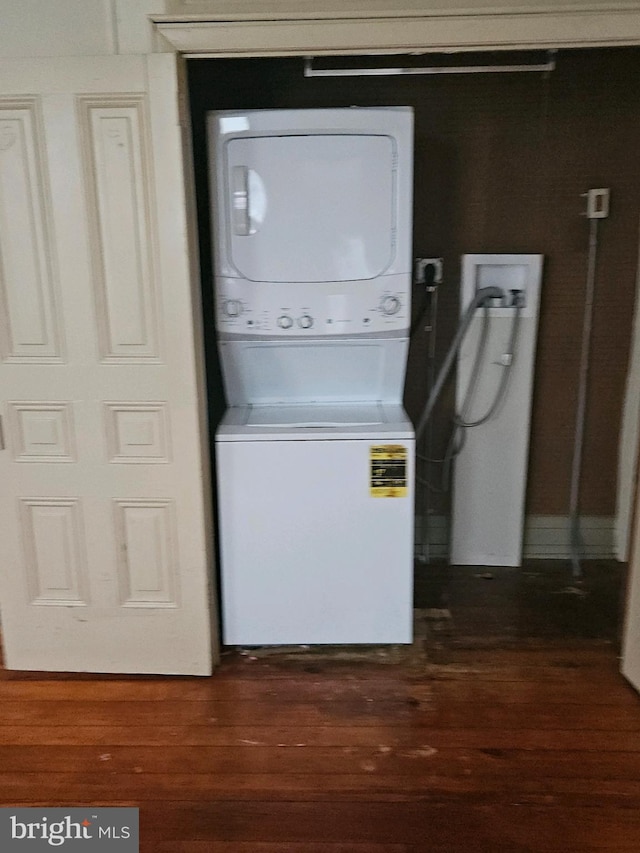 washroom with dark wood-type flooring and stacked washer and clothes dryer