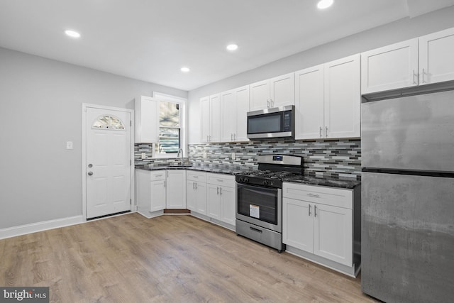 kitchen with white cabinetry, sink, tasteful backsplash, light hardwood / wood-style flooring, and appliances with stainless steel finishes