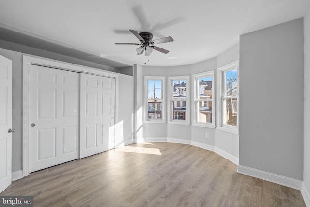 unfurnished bedroom with ceiling fan, light hardwood / wood-style flooring, and a closet