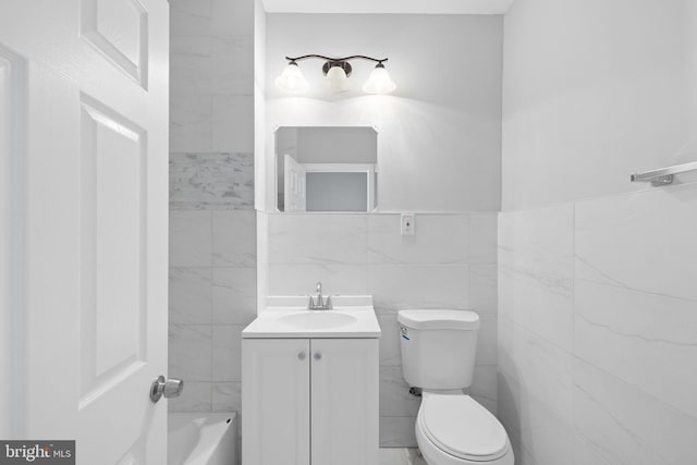 bathroom with vanity, tile walls, and toilet