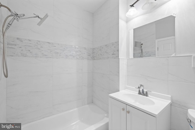 full bathroom featuring tiled shower / bath combo, toilet, tile walls, and vanity