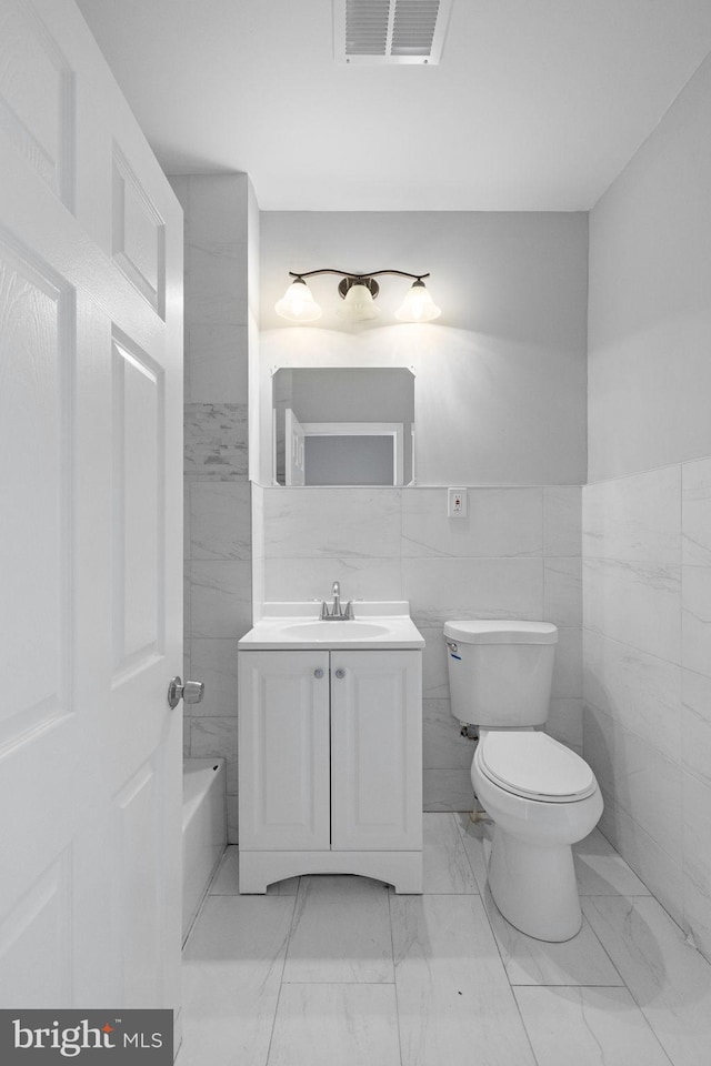 bathroom with vanity, tile walls, and toilet