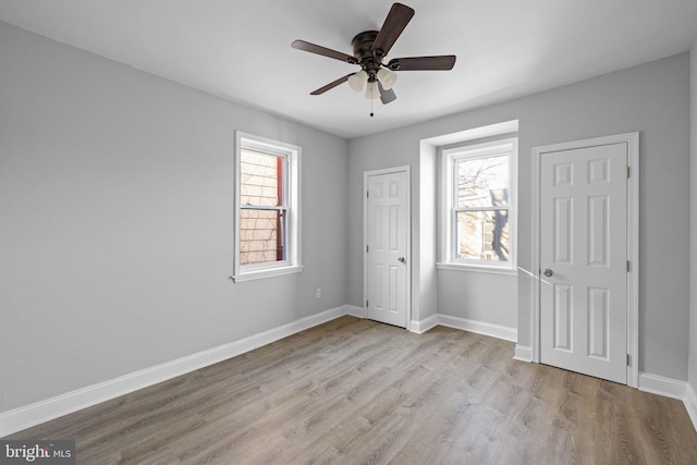 unfurnished bedroom featuring multiple windows, light wood-type flooring, and ceiling fan