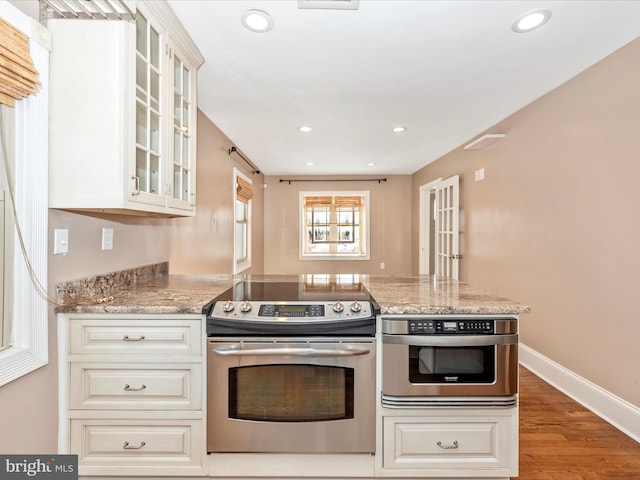 kitchen featuring white cabinets, light stone countertops, electric stove, and wood-type flooring