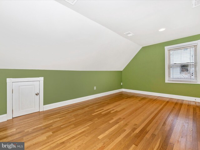 additional living space featuring light wood-type flooring and lofted ceiling