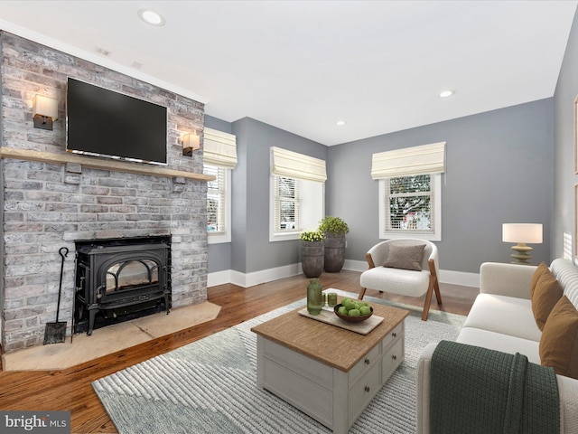 living room with a healthy amount of sunlight, a wood stove, and light hardwood / wood-style flooring