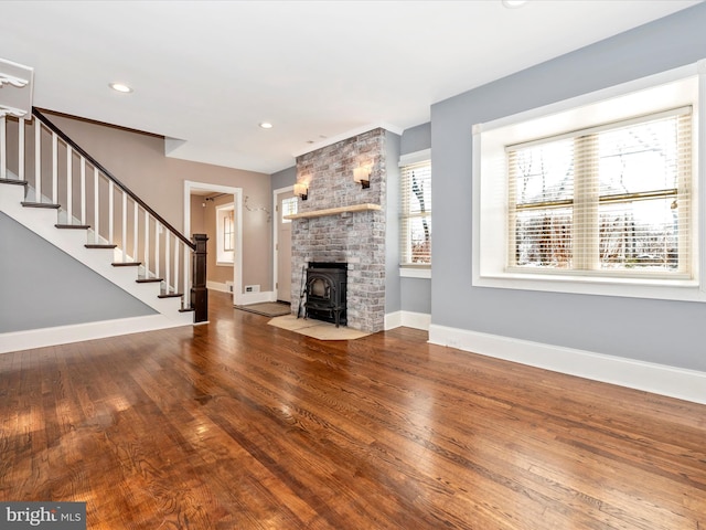 unfurnished living room featuring hardwood / wood-style floors and a wood stove