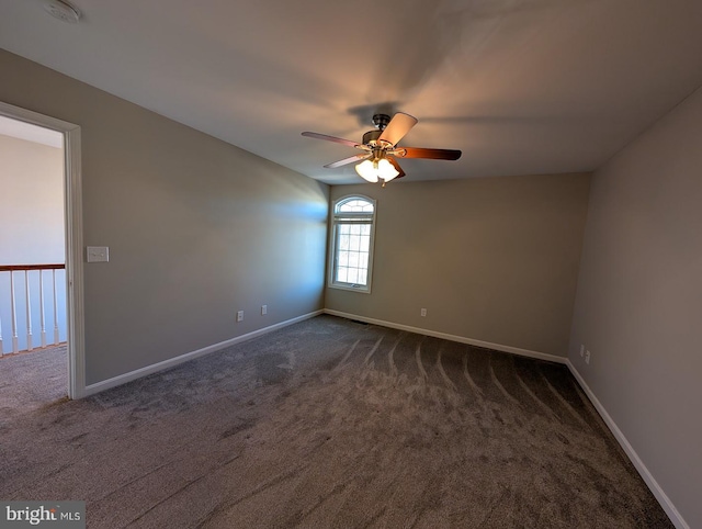 spare room with ceiling fan and dark carpet