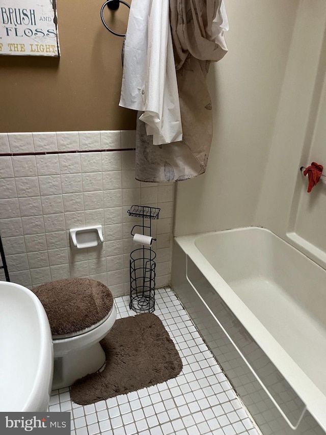 bathroom featuring sink, tile patterned flooring, toilet, tile walls, and a tub