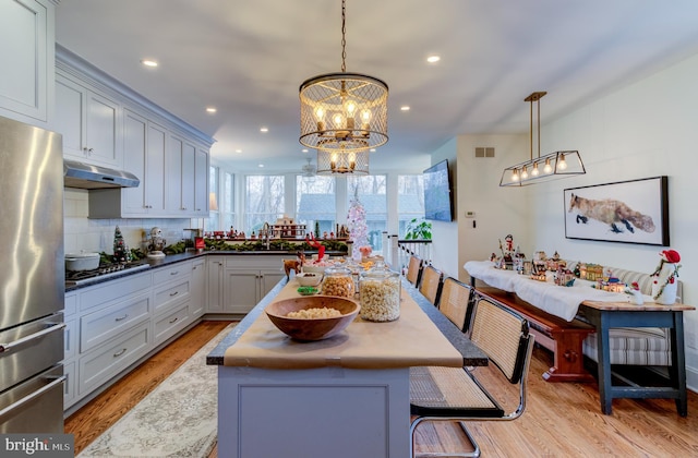 kitchen featuring a breakfast bar area, a kitchen island, stainless steel appliances, and decorative light fixtures