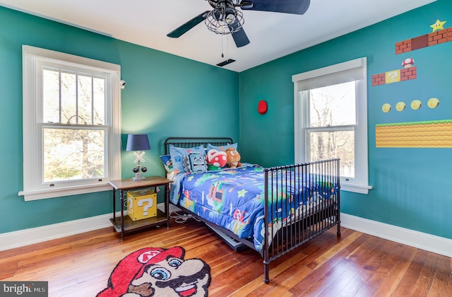 bedroom with multiple windows, wood-type flooring, and ceiling fan