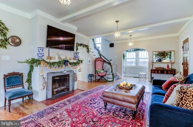 living room featuring a notable chandelier, light hardwood / wood-style floors, crown molding, and beam ceiling