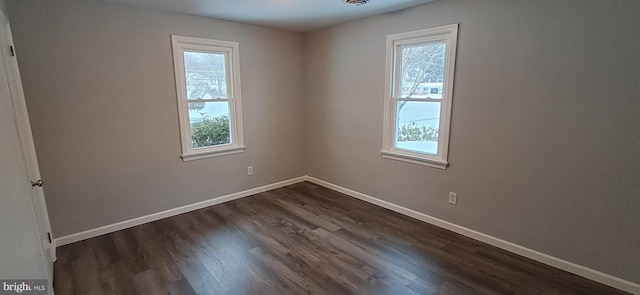 spare room featuring a healthy amount of sunlight and dark wood-type flooring