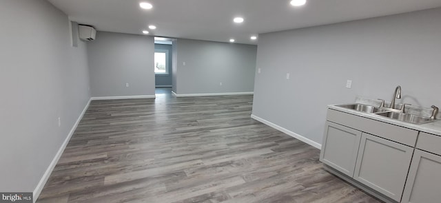 interior space with a wall mounted air conditioner, gray cabinets, light wood-type flooring, and sink