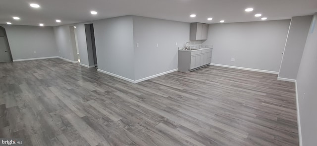 basement featuring light hardwood / wood-style flooring and sink