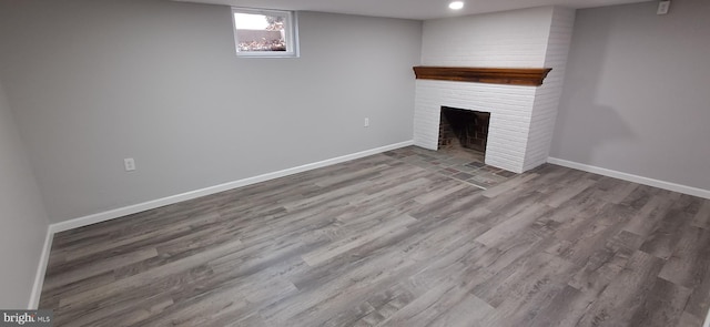 basement with a fireplace and wood-type flooring