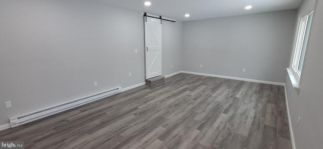 empty room with hardwood / wood-style floors, a barn door, and a baseboard radiator