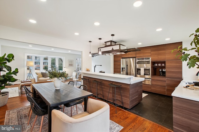 kitchen featuring kitchen peninsula, appliances with stainless steel finishes, sink, dark hardwood / wood-style floors, and hanging light fixtures