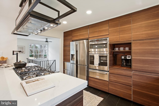 kitchen featuring ceiling fan, dark tile patterned floors, stainless steel appliances, and range hood