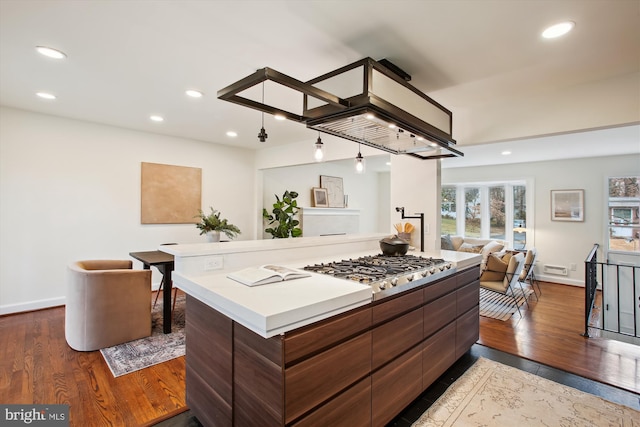 kitchen with dark hardwood / wood-style flooring, a kitchen island, and stainless steel gas stovetop