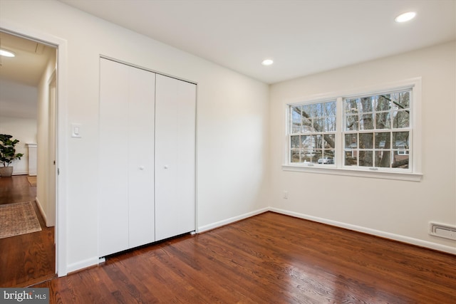 unfurnished bedroom featuring dark hardwood / wood-style flooring and a closet