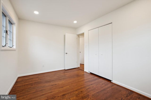 unfurnished bedroom with dark hardwood / wood-style floors and a closet