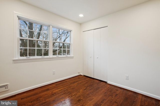 unfurnished bedroom with a closet and dark wood-type flooring