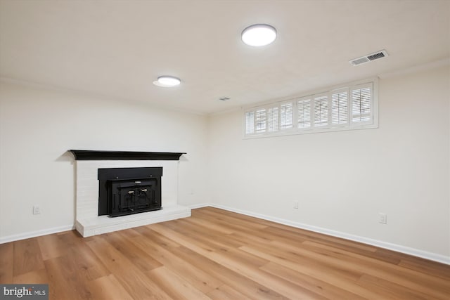 unfurnished living room featuring hardwood / wood-style flooring and a brick fireplace