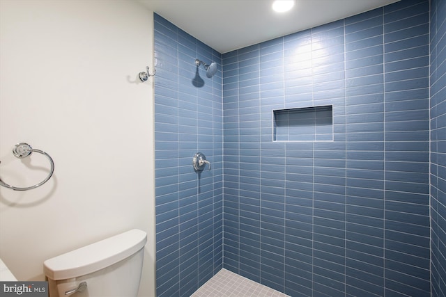 bathroom featuring tiled shower and toilet