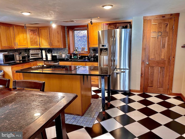 kitchen with backsplash, rail lighting, sink, a breakfast bar area, and stainless steel appliances