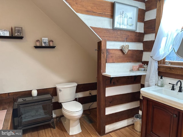 bathroom with toilet, vanity, vaulted ceiling, and hardwood / wood-style flooring