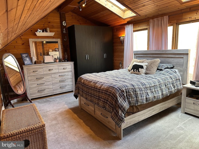 carpeted bedroom with vaulted ceiling with skylight, wood ceiling, and wood walls