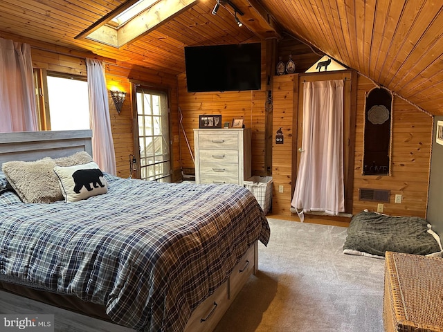 bedroom featuring wooden walls, vaulted ceiling with skylight, and wood ceiling