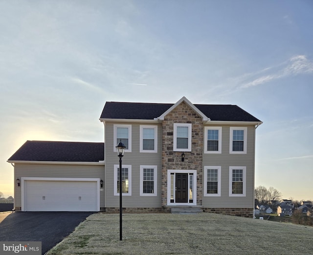 colonial home with a garage and a yard