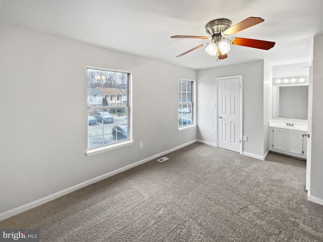 unfurnished bedroom with ensuite bath, ceiling fan, sink, and light carpet