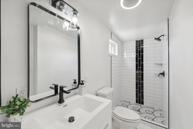 bathroom with tiled shower, toilet, and sink