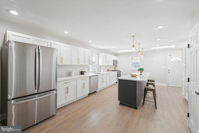 kitchen with light hardwood / wood-style floors, a kitchen island, white cabinetry, and stainless steel appliances