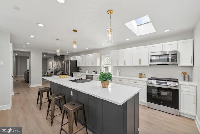 kitchen featuring pendant lighting, a center island, stainless steel appliances, and white cabinetry