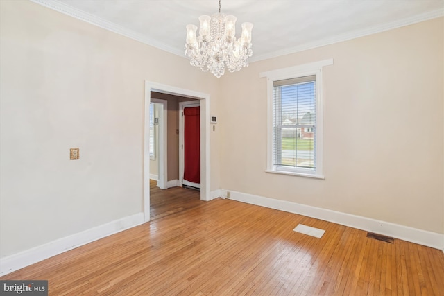 empty room with crown molding, light hardwood / wood-style flooring, and a chandelier