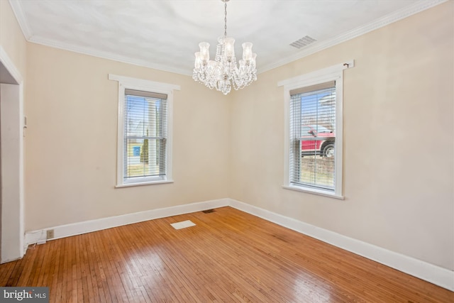 spare room featuring hardwood / wood-style floors, ornamental molding, and a notable chandelier