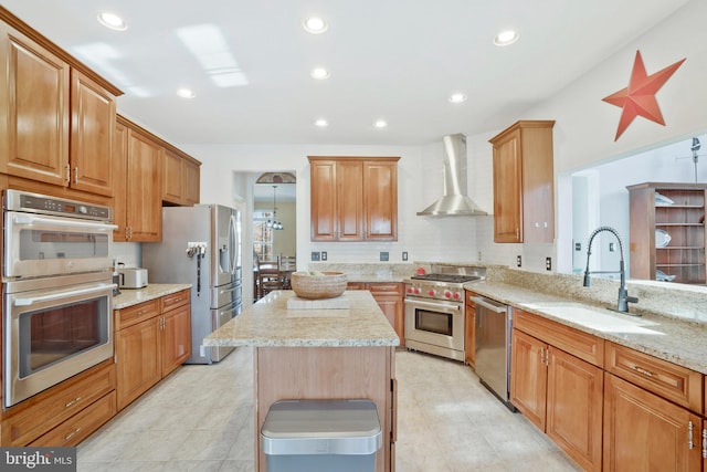 kitchen with light stone countertops, sink, a center island, stainless steel appliances, and wall chimney range hood