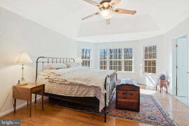 bedroom featuring hardwood / wood-style floors, ceiling fan, and a raised ceiling