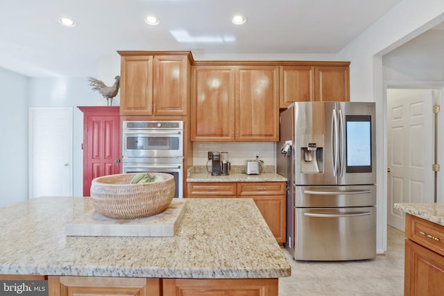 kitchen featuring light stone counters, a center island, light tile patterned floors, and stainless steel appliances