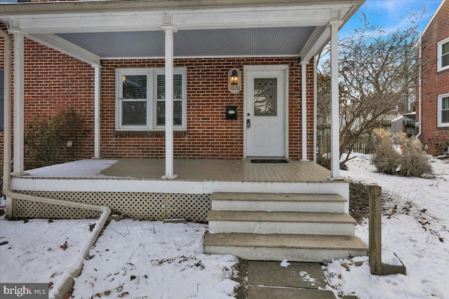 snow covered property entrance with a porch