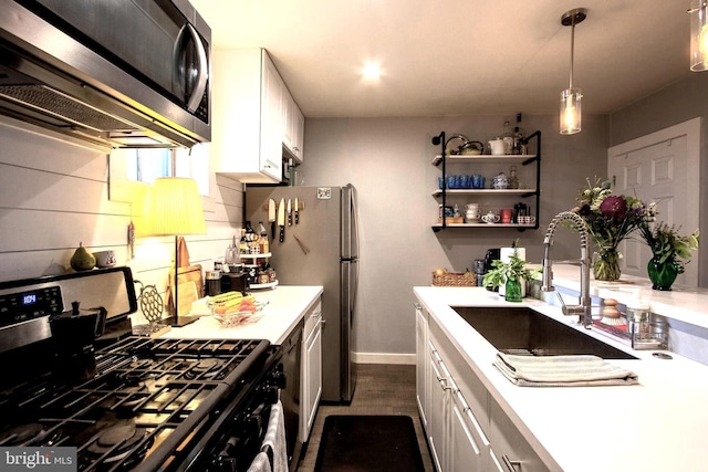 kitchen with hanging light fixtures, white cabinetry, sink, and stainless steel appliances