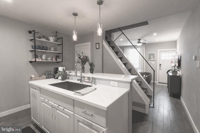 kitchen featuring baseboards, a ceiling fan, light countertops, and a sink