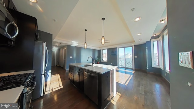 kitchen with stainless steel appliances, a kitchen island with sink, sink, decorative light fixtures, and dark hardwood / wood-style floors