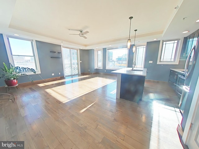 kitchen with pendant lighting, a tray ceiling, and an island with sink