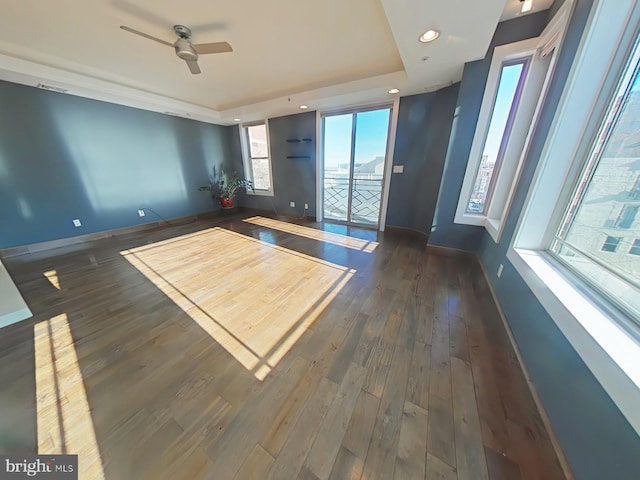 unfurnished room featuring a tray ceiling, ceiling fan, and dark hardwood / wood-style flooring